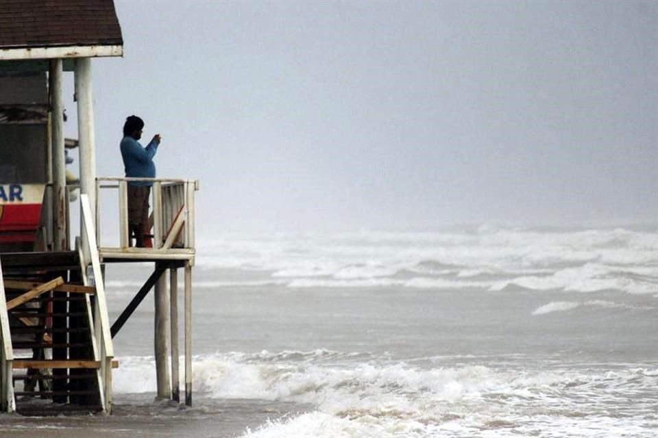 Un hombre toma una foto al mar en Playa Bagdad.