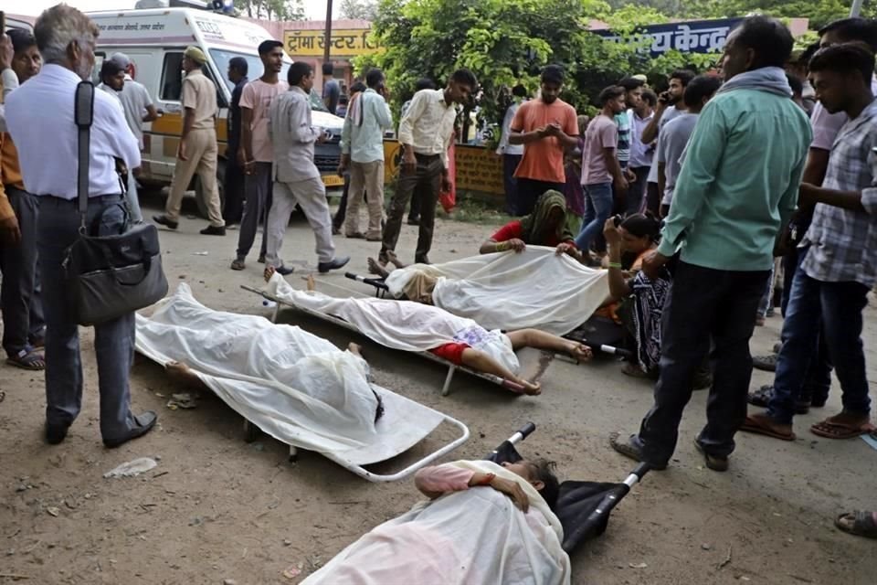La gente se encuentra alrededor de los cuerpos que yacen cubiertos en camillas afuera del hospital de Sikandrarao en el distrito de Hathras.