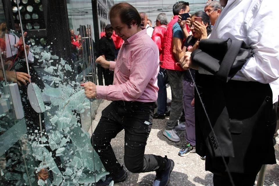 Un inconforme dio cuenta de una puerta de vidrio del acceso principal al Pepsi Center, ante la imposibilidad de ingresar a la asamblea priista.