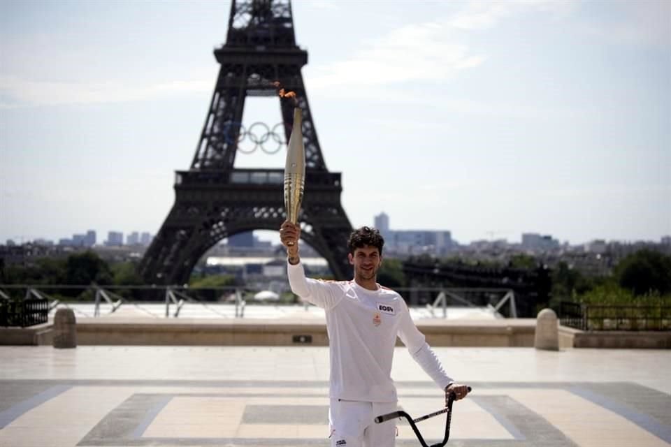 El campeón francés de BMX Matthias Dandois sostiene la antorcha olímpica frente a la Torre Eiffel durante el recorrido de la llama por París.