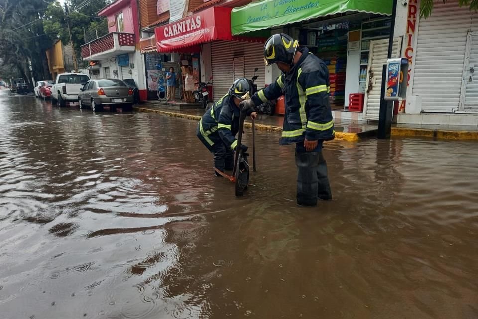 Bomberos de la CDMX laboran para desazolvar calles que se encuentran inundadas por las lluvias.