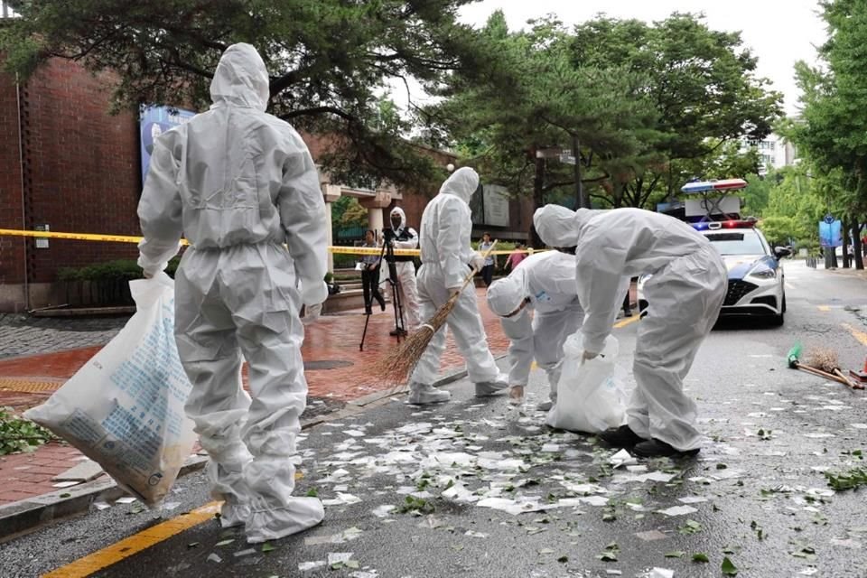 Personal surcoreano limpia los contenidos de globos con basura lanzados por Corea del Norte en una calle de Seoul.