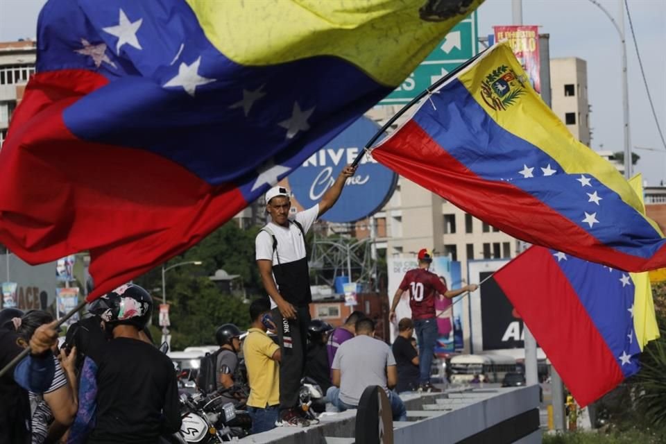 Seguidores de la oposición sostienen banderas de Venezuela en un mitin de Edmundo Gonzalez y María Corina Machado.