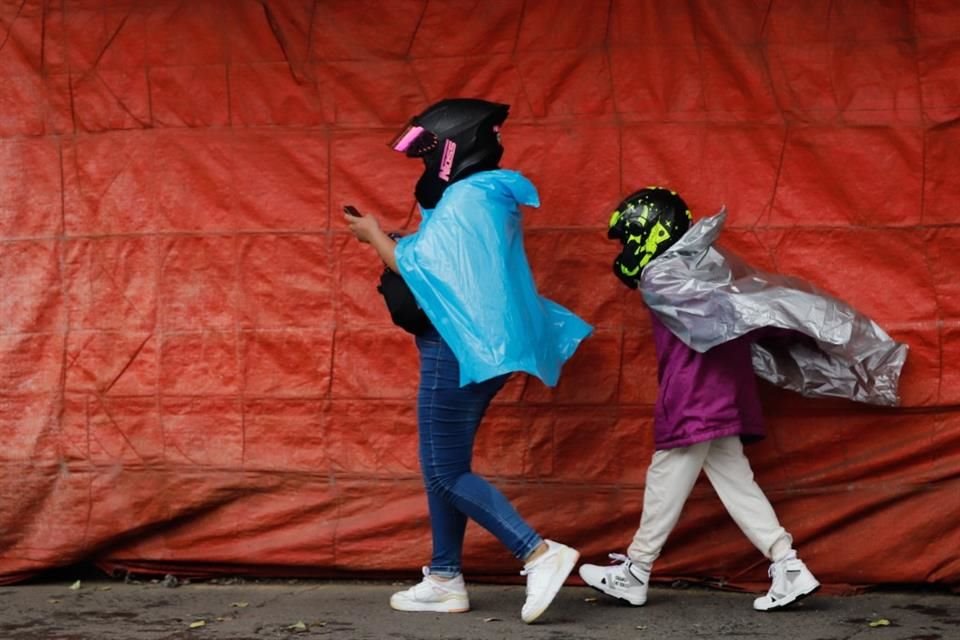 Capitalinos recurrieron a bolsas de plástico para cubrirse durante una tormenta.