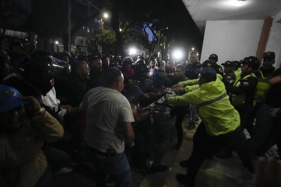 Simpatizantes del gobierno agarran a un partidario de la oposición mientras oficiales de la policía intervienen durante la elección presidencial en Caracas, Venezuela, el 28 de julio de 2024.