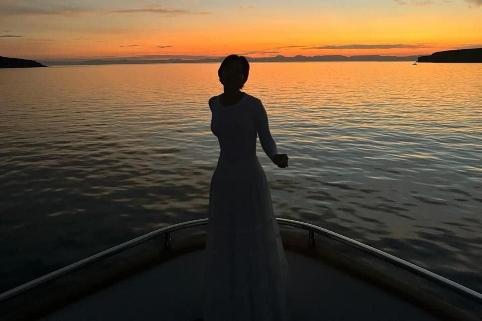 Ángela, de 20 años, posando con un elegante vestido blanco, con el atardecer como telón de fondo.