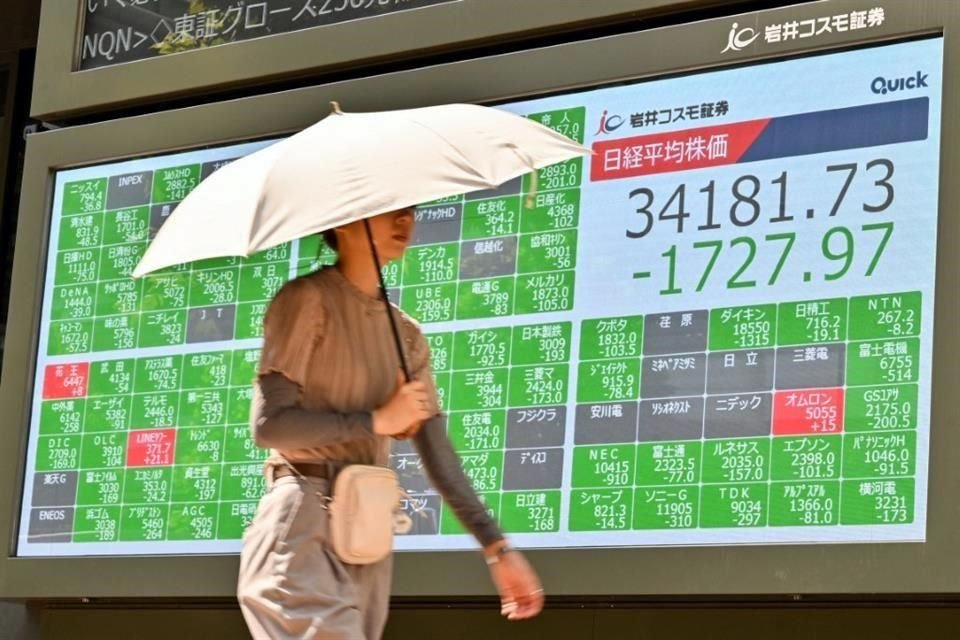 Un peatón pasa junto a un cartel que muestra los números de la mañana en la Bolsa de Valores de Tokio a lo largo de una calle de Tokio el 5 de agosto de 2024.