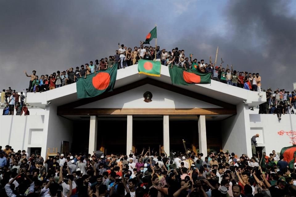 Manifestantes ondean banderas de Bangladesh en la residencia de la Primer Ministra Sheikh Hasina.