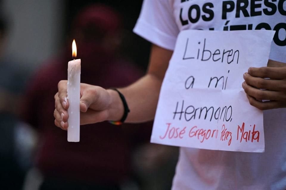 Un hombre sostiene una vela y un cartel durante una vigilia por los presos políticos en Caracas, Venezuela.