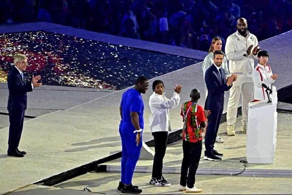 El presidente del Comité Organizador de los JO París 2024, Tony Estanguet (der.), es acompañado por el presidente del Comité Olímpico Internacional, Thomas Bach (izq.), y otros emblemáticos  atletas.