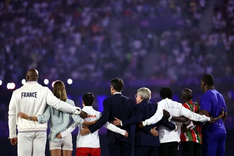 Tony Estanguet (centro-izq.), y Thomas Bach (centro-der.), posan con atletas en el himno olímpico.