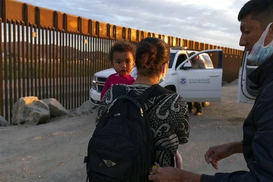 Una mujer con su bebé, en Arizona, espera para ser procesada por las autoridades de EU luego de cruzar ilegalmente la frontera.