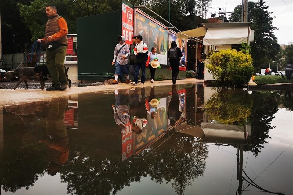 Las fuertes lluvias de ayer dejaron espejos de agua, los cuales reflejan el pasar de los peatones. 