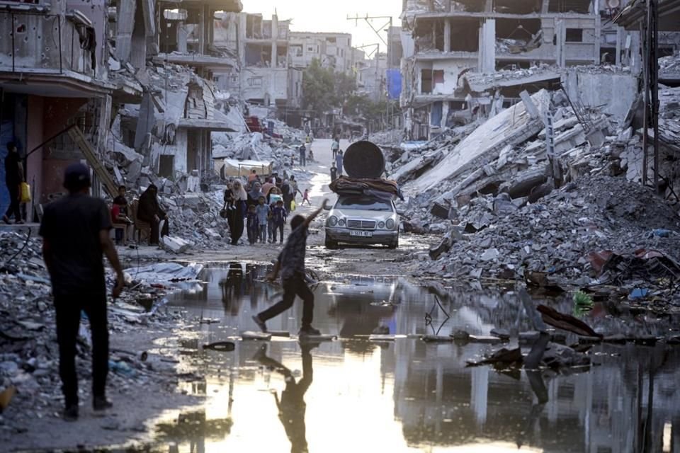 Palestinos desplazados por la ofensiva terrestre y aérea de Israel en la Franja de Gaza caminan cerca de aguas residuales en las calles de Jan Yunis, el 4 de julio de 2024.