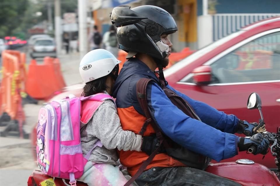 Trasladan a sus hijos en medio del tráfico.