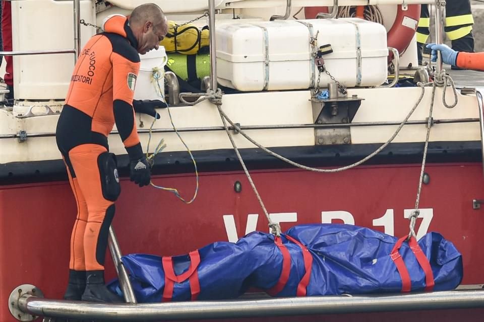 Buzos del cuerpo de bomberos de Italia suben a bordo una bolsa de plástico con el cuerpo de una de las víctimas de un naufragio en Porticello, Sicilia, en el sur de Italia, el 22 de agosto de 2024.