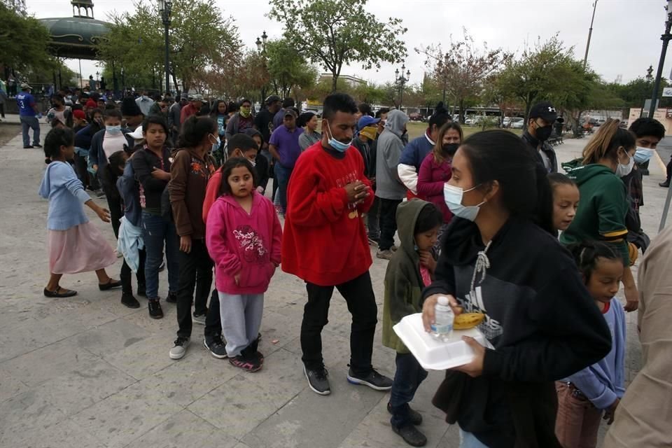 Migrantes centroamericanos reciben una comida en Reynosa tras ser deportados de EU.