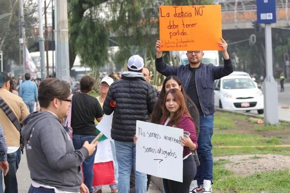 Manifestantes con carteles que dicen 'no somos acarreados, somos abogados' y 'la justicia no debe tener partido'.