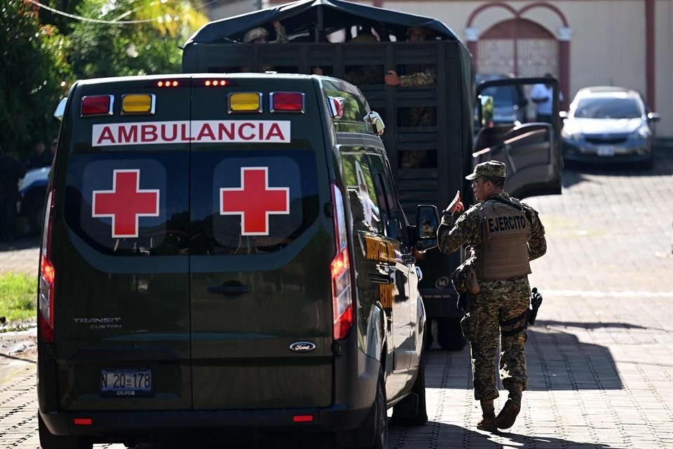 Un soldado camina junto a una ambulancia cerca de donde un helicóptero se estrelló el El Salvador.