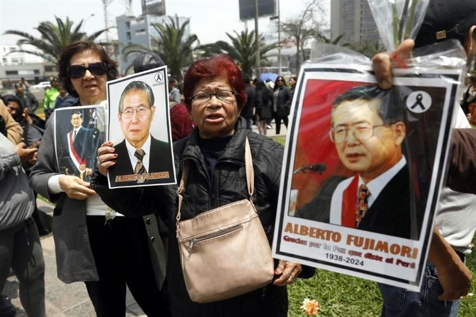 Simpatizantes del expresidente peruano, Alberto Fujimori, sostienen fotografías mientras hacen fila para ingresar a su funeral, en el Museo de La Nación, en Lima, Perú.