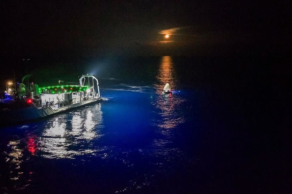 Con la luna de fondo sobre el mar, un barco se acercaba para recoger a los tripulantes.