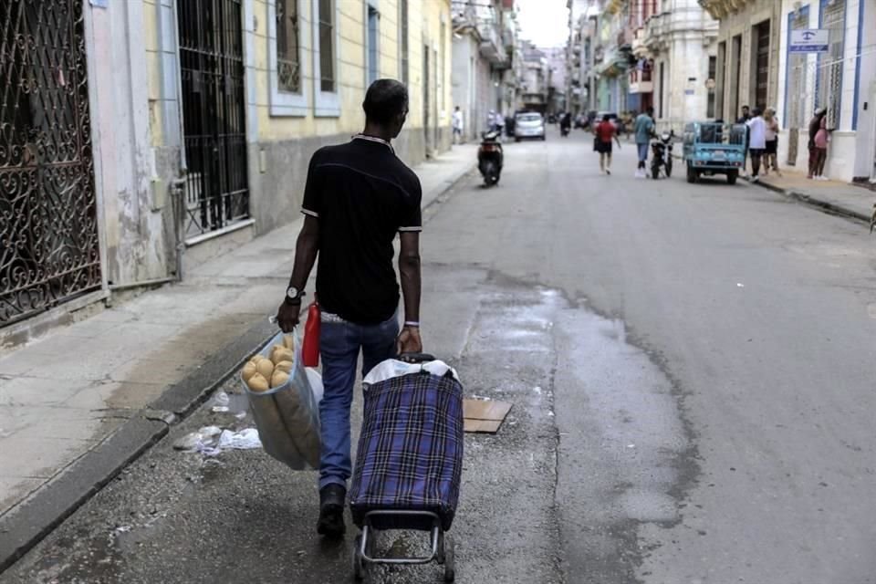 Un hombre lleva un carro de la compra con una bolsa llena de pan, en La Habana. Durante 60 años la libreta de abastecimiento fue el pilar de la alimentación en la isla.