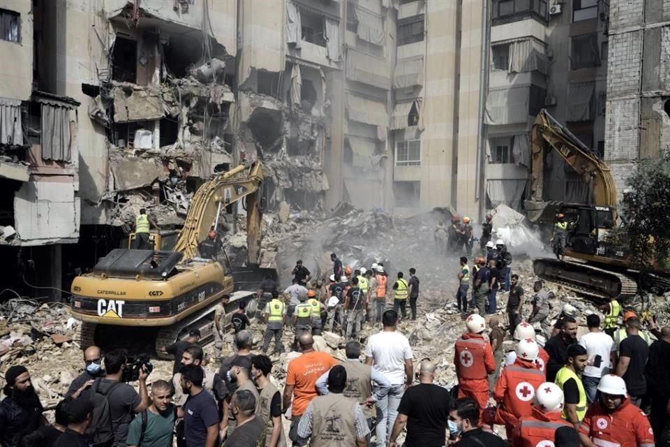 Los trabajadores de emergencia utilizan excavadoras para limpiar los escombros en el lugar del ataque israelí.