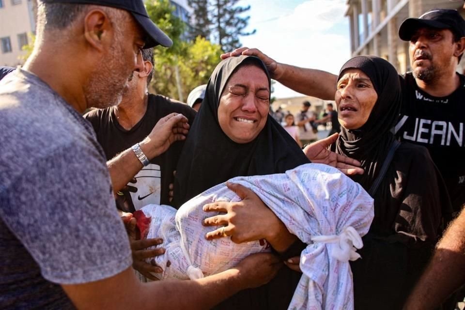 Una mujer llora mientras sostiene el cuerpo amortajado de su hijo que murió durante un ataque israelí contra una escuela que albergaba a palestinos desplazados en el barrio Zaytoun.