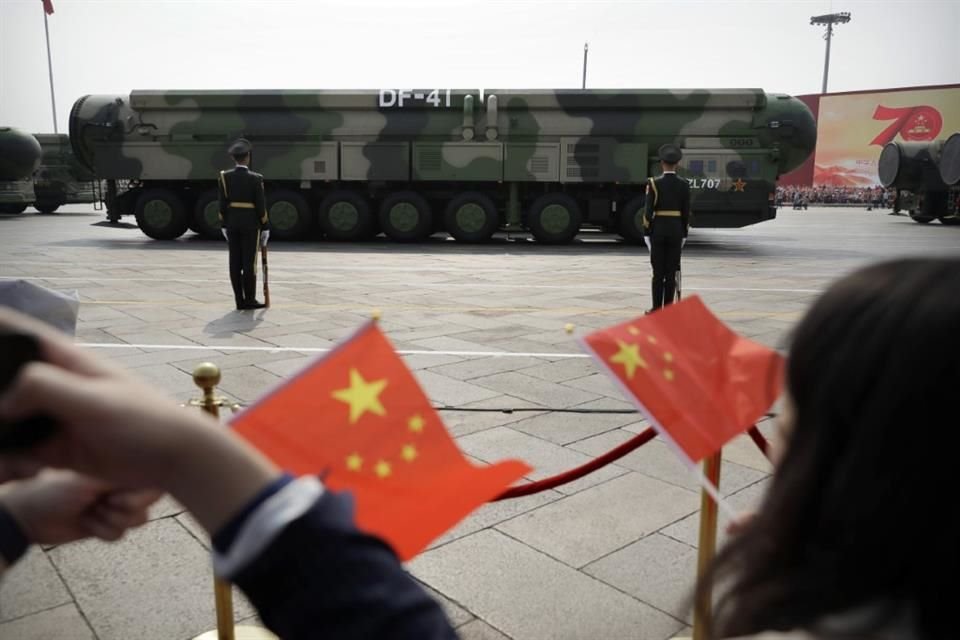 Espectadores ondean banderas chinas mientras vehículos militares con misiles balísticos desfilan en el 70 aniversario de la fundación de la China comunista en Beijing.