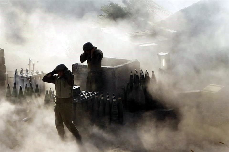 Soldados de artillería israelíes están rodeados de humo y polvo mientras disparan a través de la frontera hacia el sur del Líbano desde una posición en la frontera en Zaura, al norte de Israel.