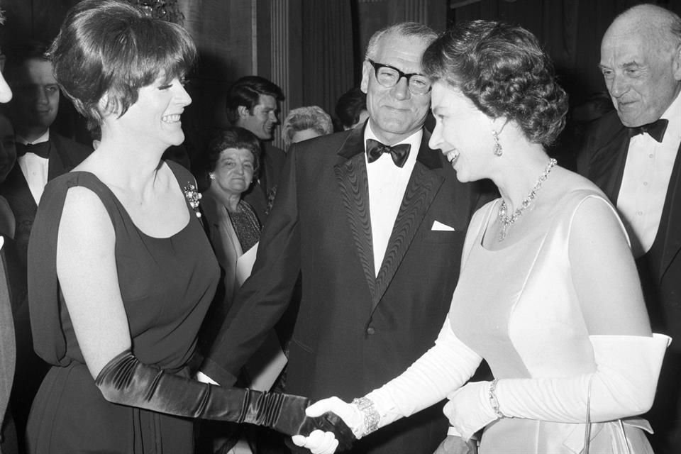 La Reina Isabel II, a la derecha, es presentada a Maggie Smith por Laurence Olivier, al centro, durante el estreno benéfico de la película Othello, en el Teatro Odeon de Londres, el 2 de mayo de 1966.