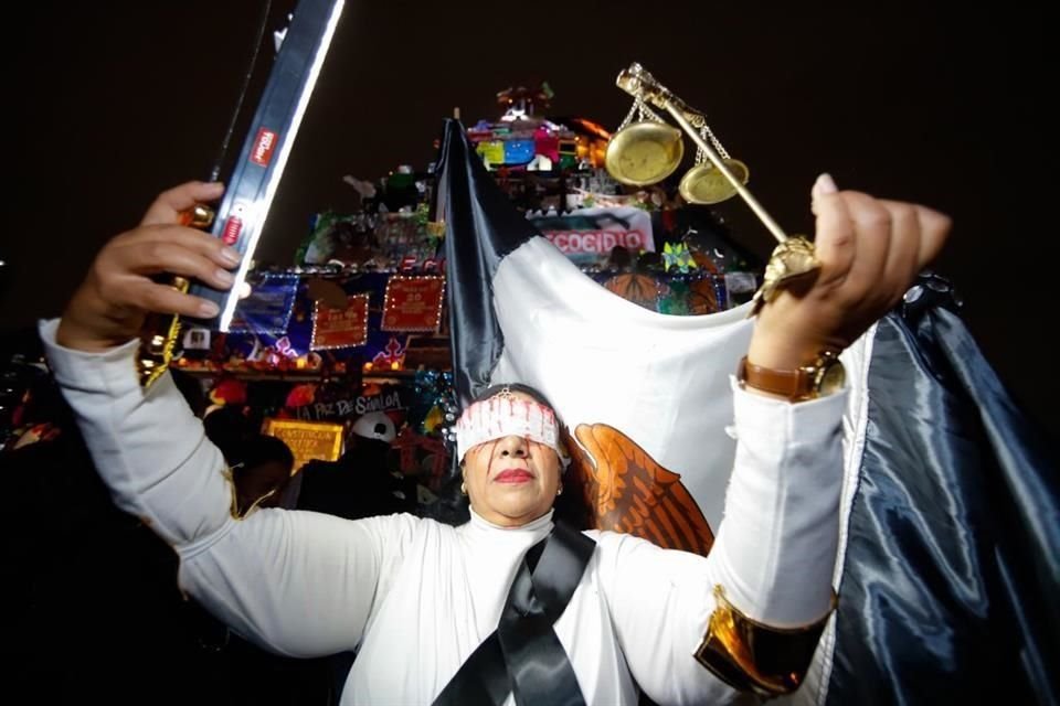 Una mujer vestida de diosa de la justicia, con una venda en los ojos manchada de sangre, hizo guardia todo el tiempo a pie de la ofrenda.