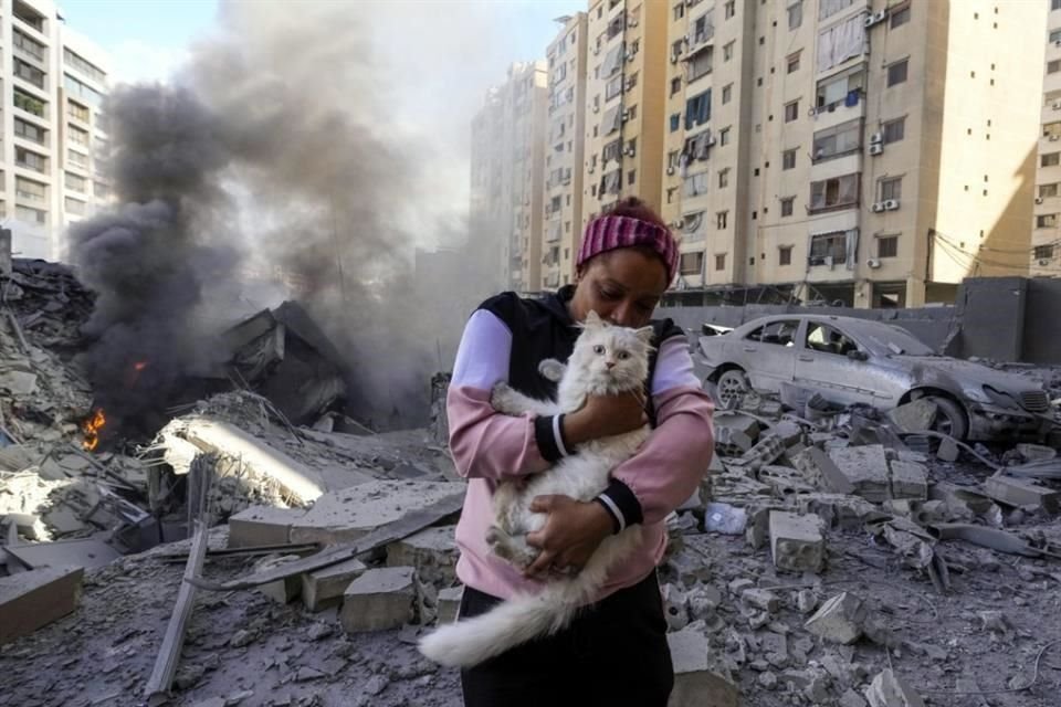 Una mujer sostiene a su gato frente a un edificio destruido en el lugar de un ataque aéreo israelí en Dahiyeh, Beirut, Líbano.