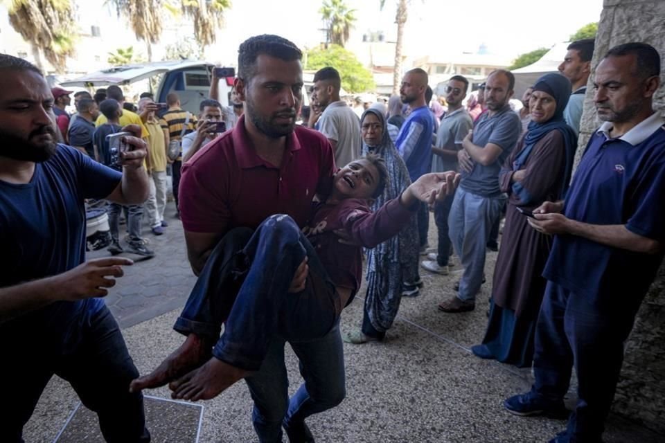 Un hombre palestino carga a un niño herido después de un ataque aéreo israelí en Deir al Balah, Franja de Gaza.