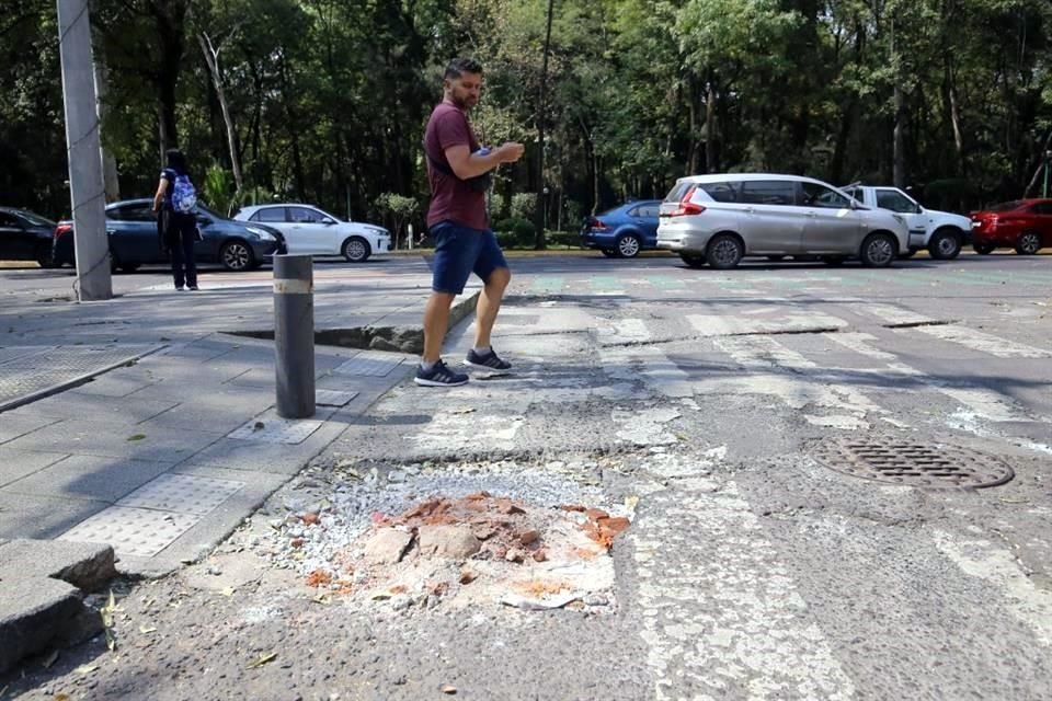 Además de hoyos en aceras, peatones lidian con baches en calles.