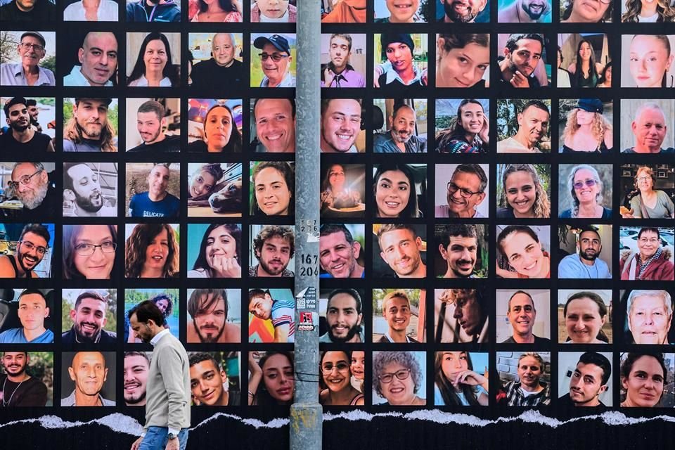 Un hombre camina junto a fotos de rehenes israelíes secuestrados por Hamas, el 25 de noviembre del 2023, en Jerusalén.