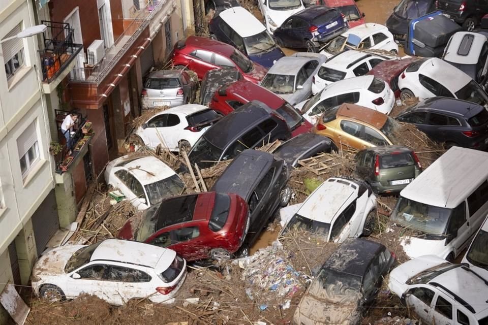 Varios vehículos quedaron apilados mientras residentes observan el desastre desde sus balcones.