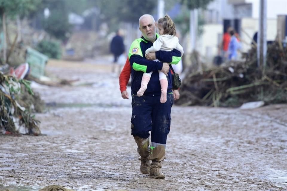 TOPSHOT - A Civil Un miembro de protección lleva a un niño en una calle cubierta de barro en una zona inundada en Picanya, cerca de Valencia.