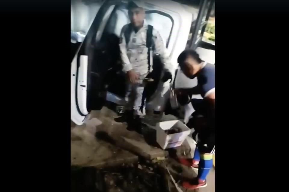 Uno de los guardias nacionales intentó meter en una bolsa negra varias botellas con bebidas alcohólicas.