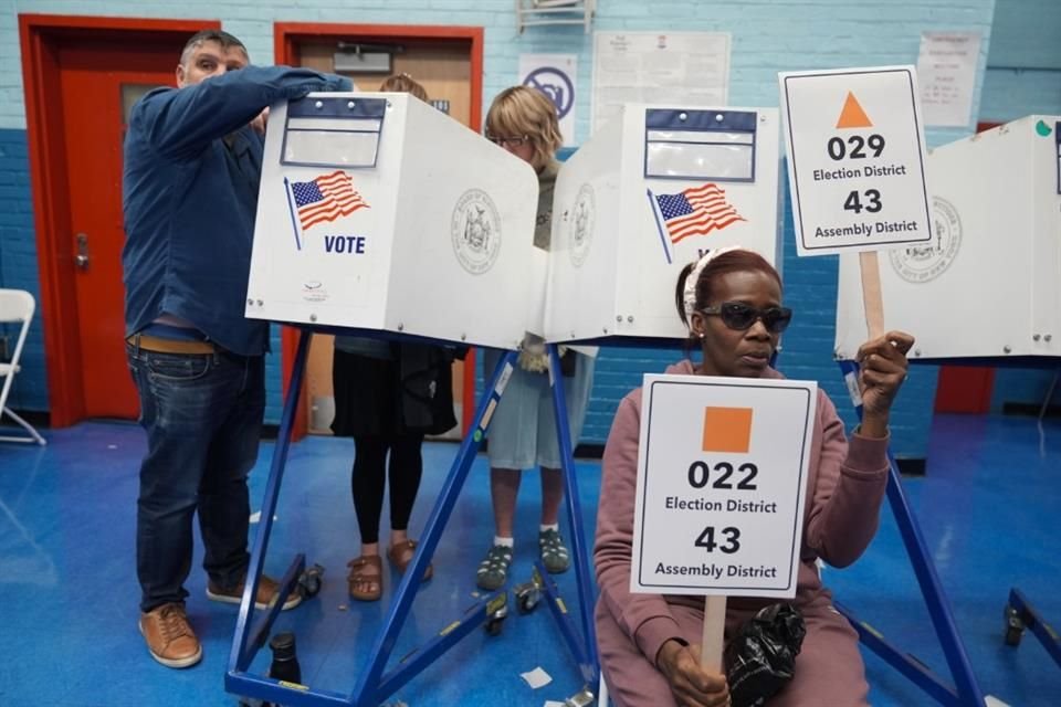 La trabajadora electoral Marion Jordan-Mcfarlane ayuda a los votantes a recoger sus papeletas en un concurrido centro de votación en el distrito de Brooklyn en Nueva York.