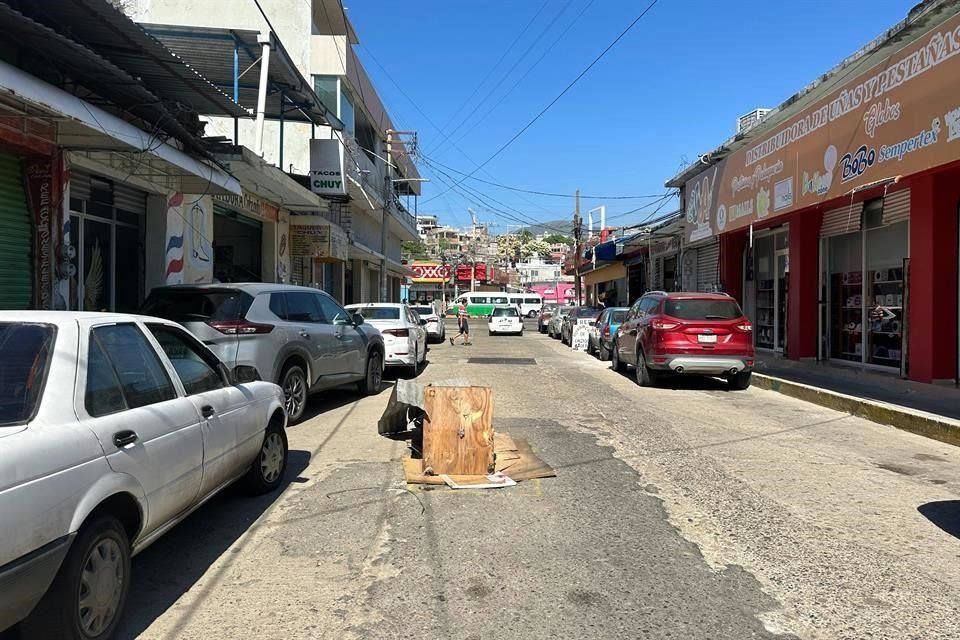 Comerciantes del mercado central utilizaron basura y troncos de madera para tapar un bache en la Calle El Canal, en la Colonia Centro.