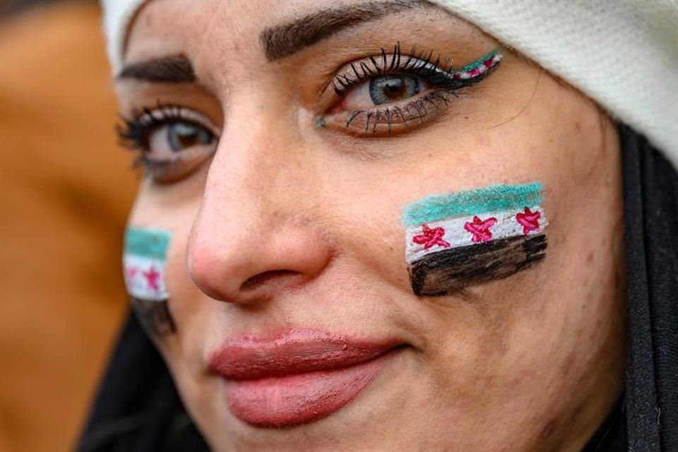 Una mujer con banderas de la oposición siria en sus mejillas observa a los residentes sirios en Turquía celebrar el fin del gobierno de Assad.