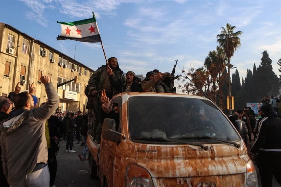 Los combatientes rebeldes sirios celebran cerca de la Torre del Reloj en Homs.