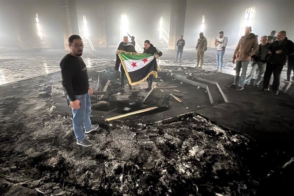 Combatientes rebeldes sostienen la bandera de la revolución en la tumba quemada del difunto presidente de Siria, Hafez al-Assad.