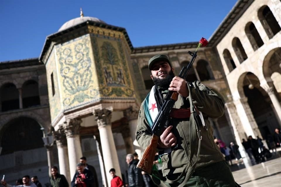 Un combatiente rebelde posa para una fotografía antes de la oración del mediodía del viernes en la mezquita de los Omeyas en Damasco, Siria.