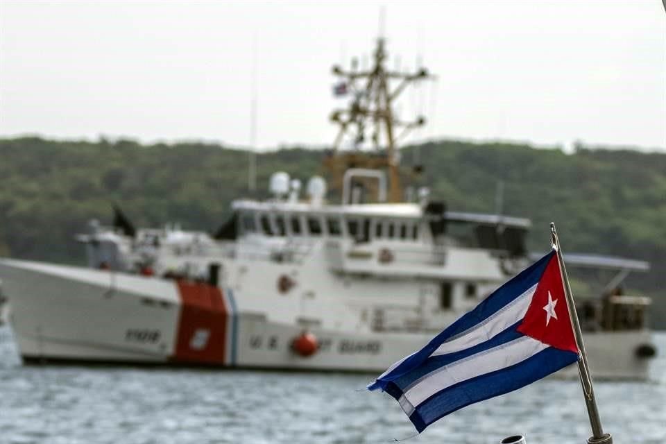 Vista de una bandera cubana y al fondo un buque de la guardia cubana.