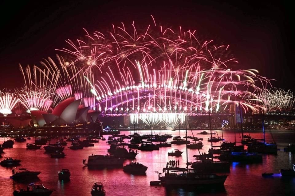 Los fuegos artificiales iluminan el cielo de medianoche sobre el Puente del Puerto de Sídney y la Ópera de Sídney durante las celebraciones.