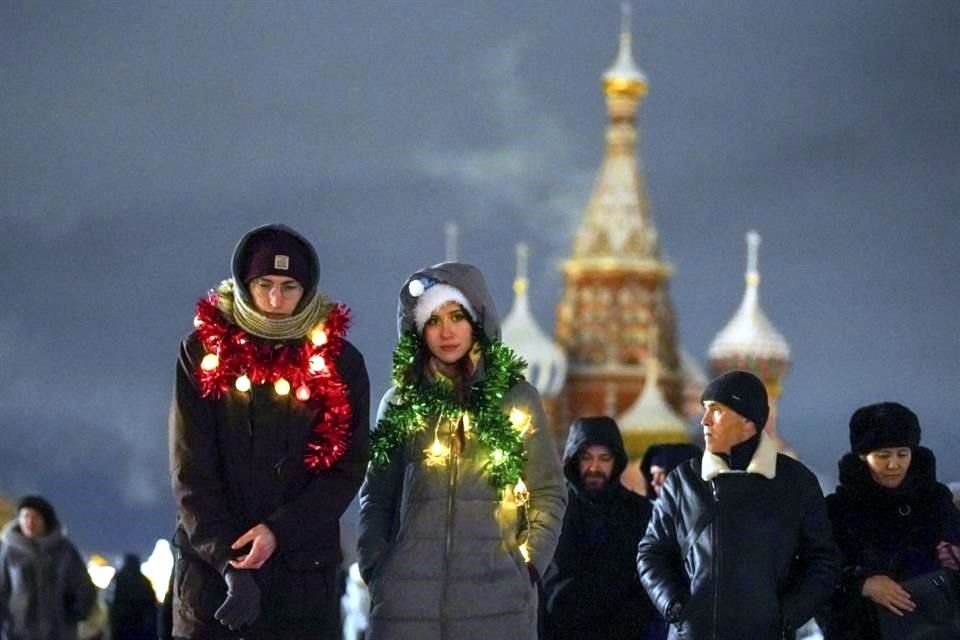 La gente camina en la Plaza Roja con la Catedral de San Basilio al fondo antes de su cierre para las celebraciones de la víspera de Año Nuevo en Moscú, Rusia.