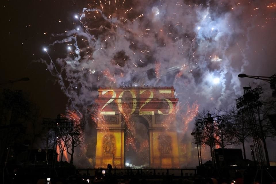 Fuegos artificiales iluminan el cielo alrededor del Arco del Triunfo en la Avenida de los Campos Elíseos de París a principios del 1 de enero de 2025, durante las celebraciones de Año Nuevo.