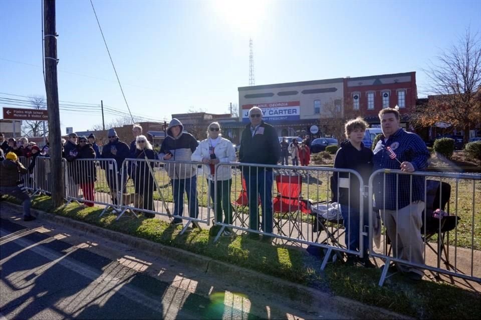 La gente se alinea en la calle en Plains, Georgia, antes de que el coche fúnebre que transporta el ataúd del ex presidente Jimmy Carter pase por la ciudad.